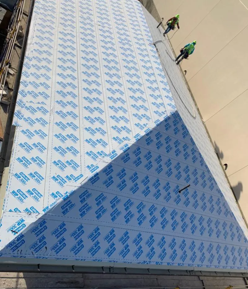 Professional roofers installing underlayment on a metal roof in Bedford